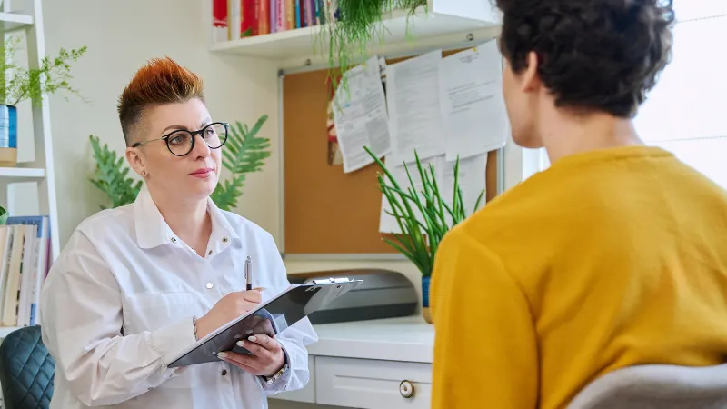 Young man meeting with counselor who is taking notes on a clipboard