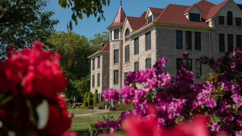 Furman Hall with brightly colored rhododendron bushes in the foreground