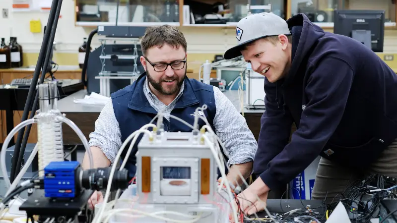 An engineering student and instructor in a classroom testing equipment 